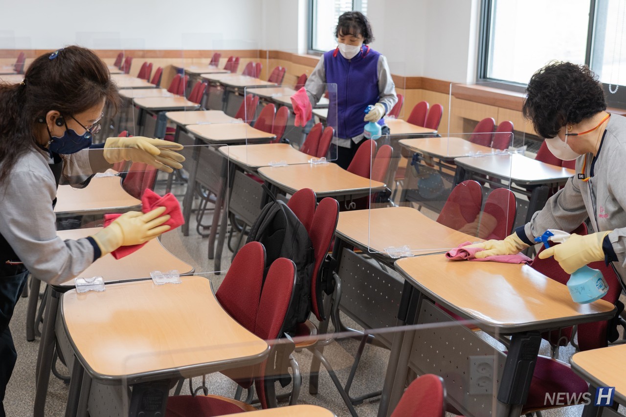 ▲下课后，清洁员们在第二工学馆对教室的桌子和隔板进行仔细地消毒作业