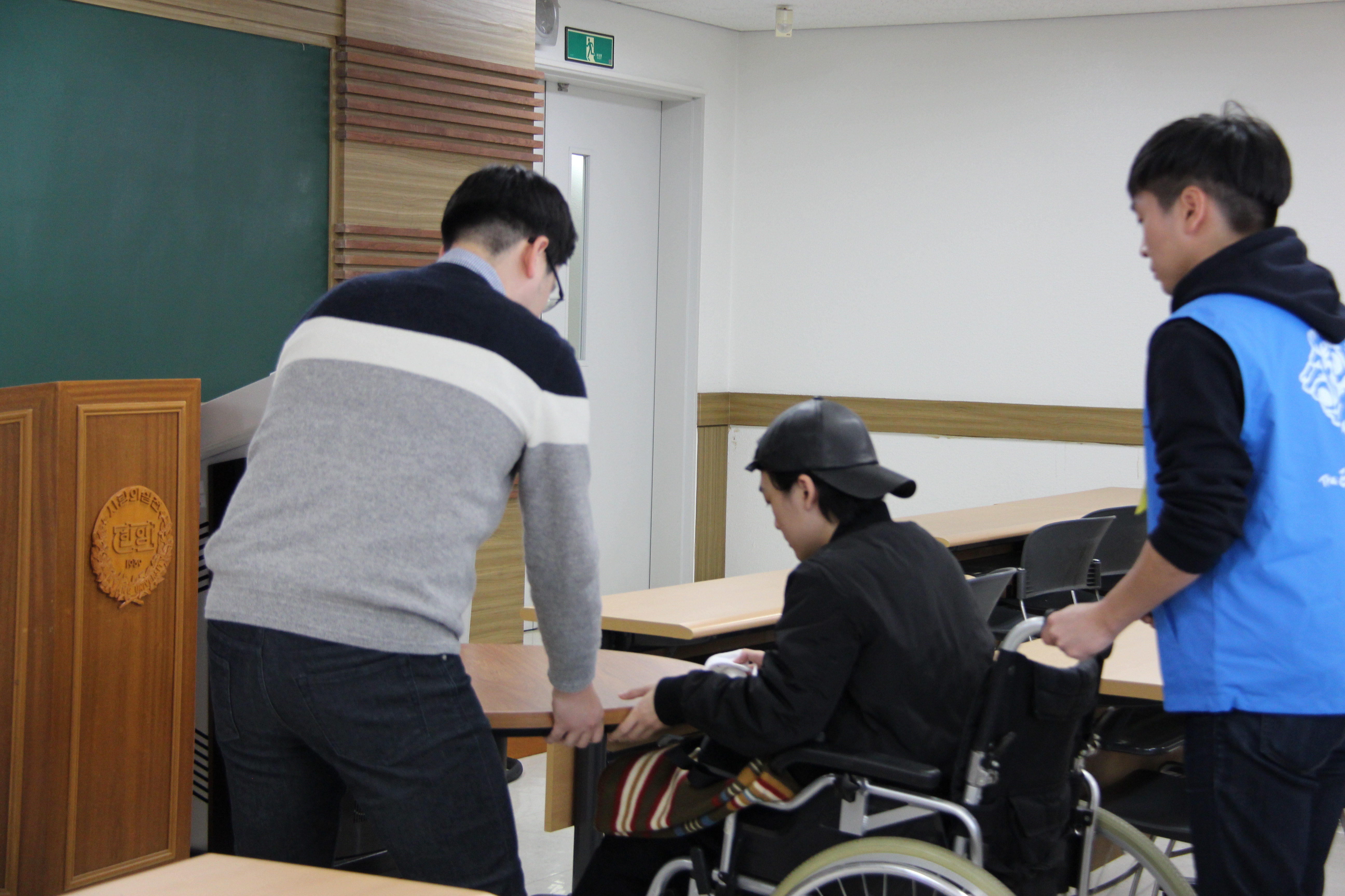 휠체어를 탄 수험생이 안내요원의 도움을 받아 시험을 준비하고 있는 모습