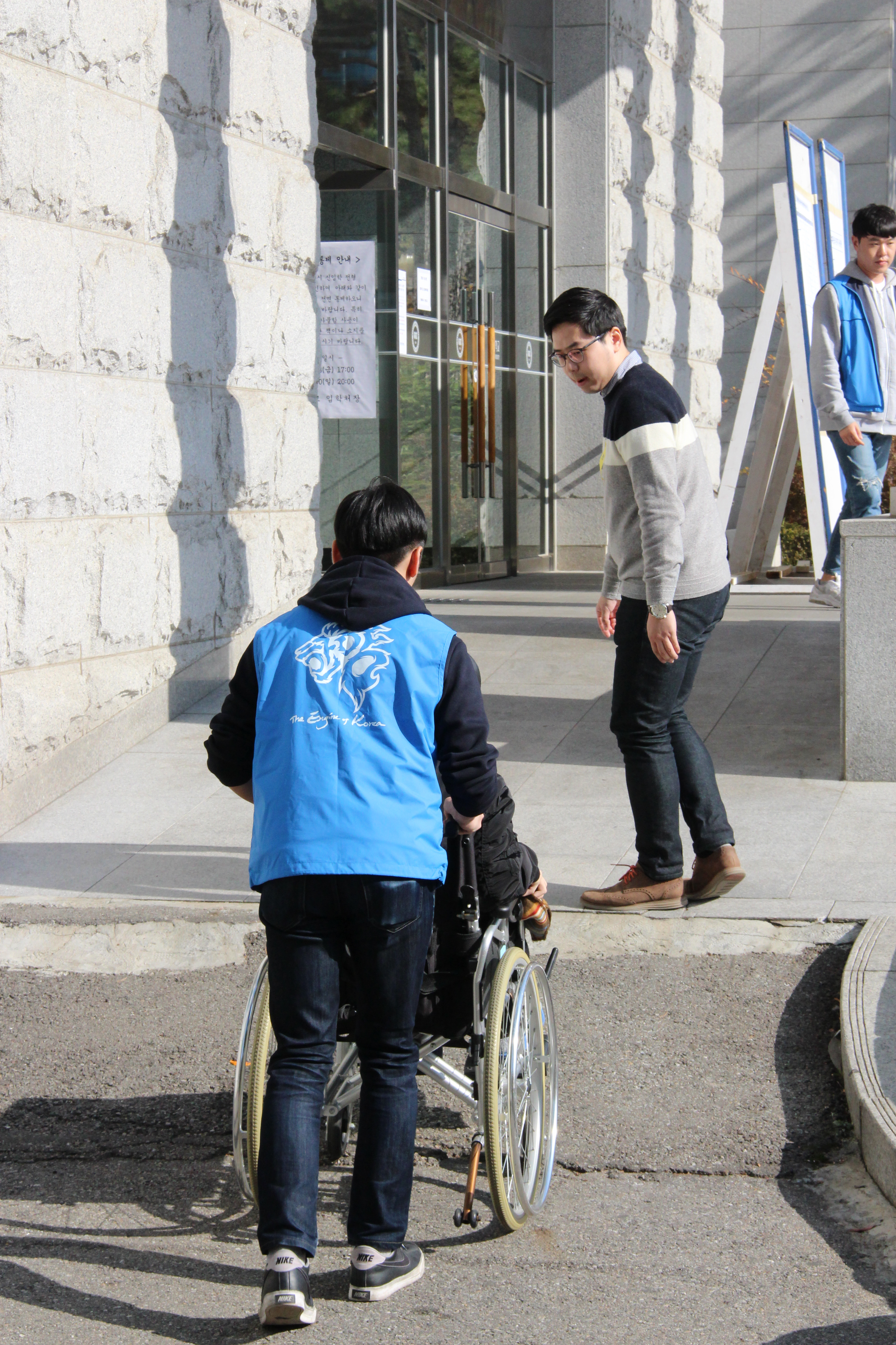 휠체어를 탄 수험생이 안내요원의 도움을 받아 고사장으로 이동하는 모습