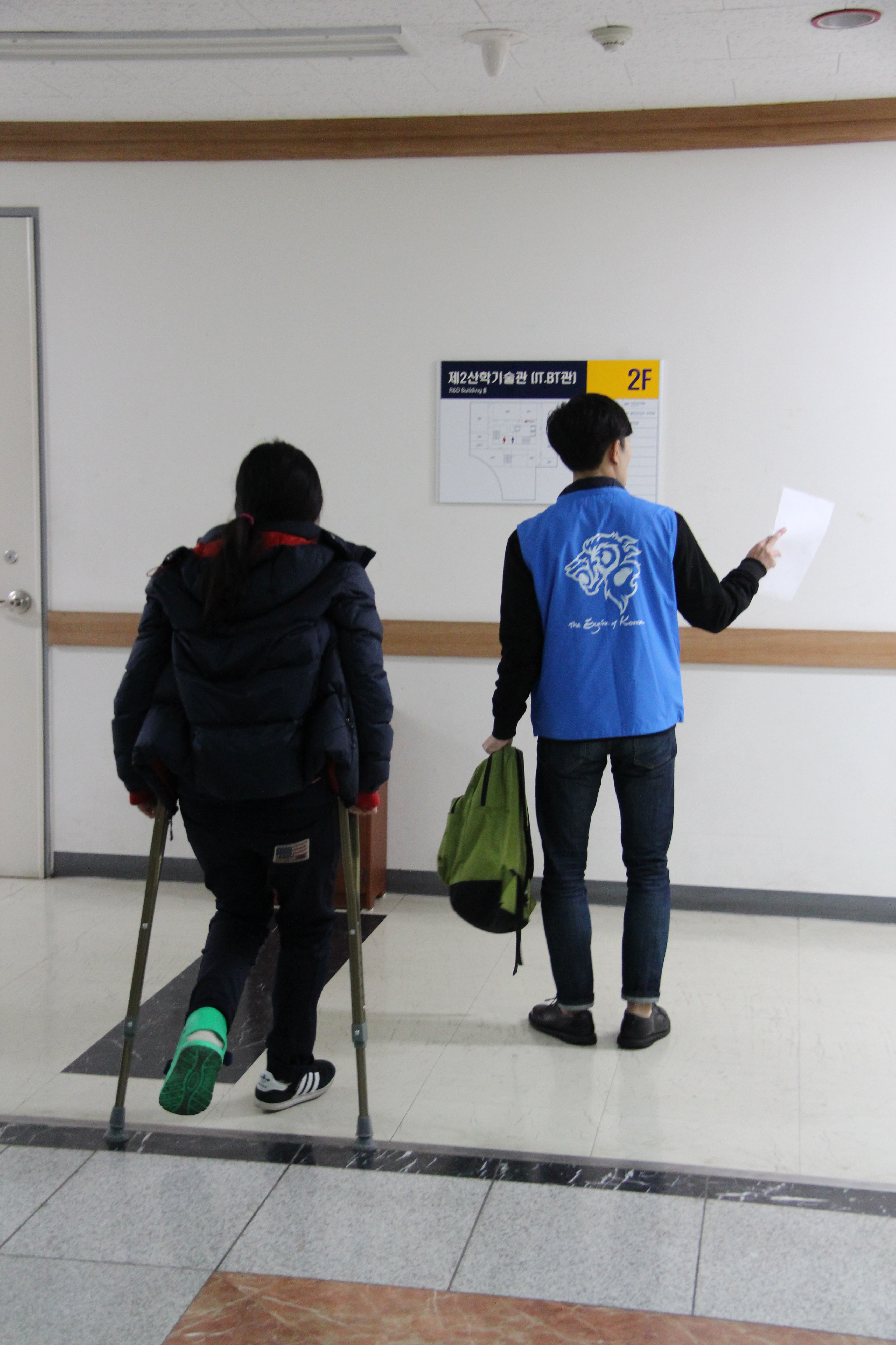 목발을 짚은 수험생이 안내요원의 도움을 받아 고사장으로 향하는 모습