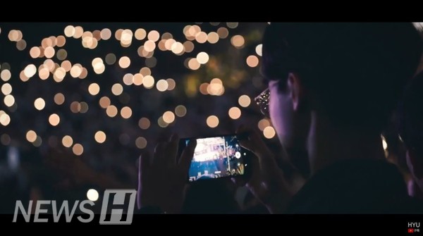 한 학생이 핸드폰 불빛으로 반짝이는 노천극장을 담고 있다 (ⓒ한양대 공식 유튜브)