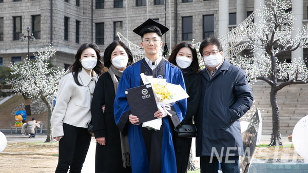 17日，在首尔城东区首尔校区里，毕业生正在和家人一起拍摄纪念照片。