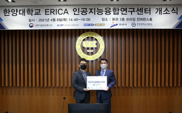 김정룡 인공지능융합연구센터장과 김정삼 과학기술정보통신부 소프트웨어정책관이 현판을 들고 기념촬영을 하고있다.