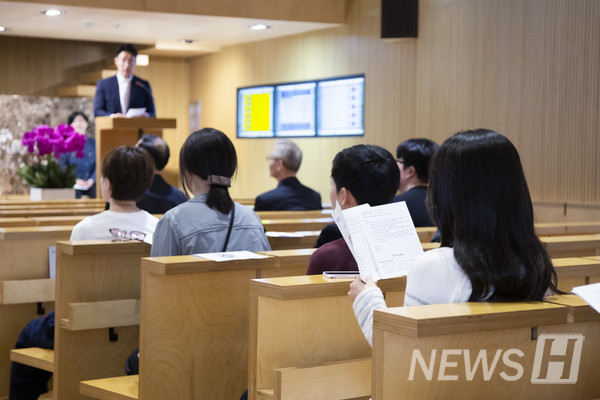 ▲ 한 신도가 목사의 인도를 들으며 예배 순서지를 읽고 있다.