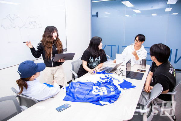 ▲ Members of the 라오스 스포츠토토 planning team discuss revisions regarding the sleeve length of the merchandise.
