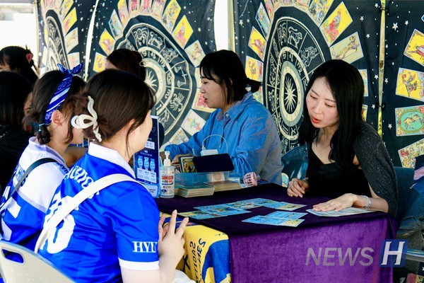▲ Students try their luck at the tarot reading booth.