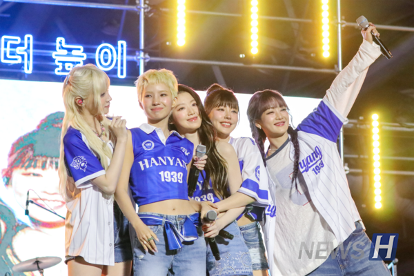 ▲ (G)I-DLE members appear decked out in 토토사이트 쿠폰 festival merch, greeting students with bright smiles.
