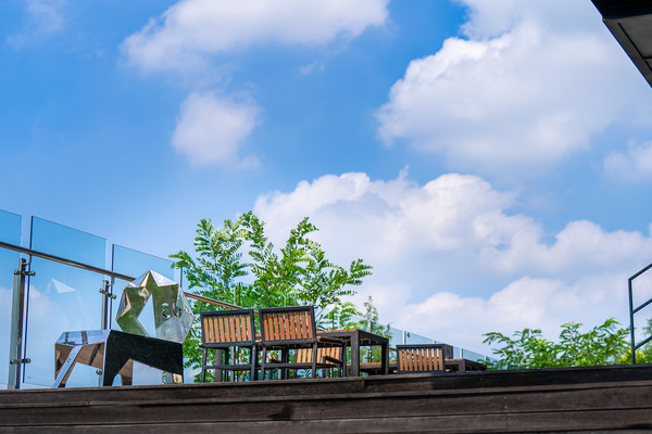 Tables and sculptures on the terrace bask under the blue sky.