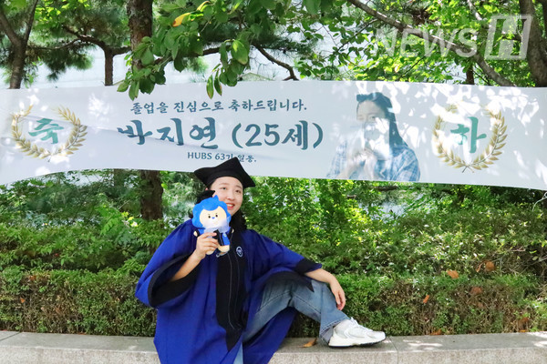 ▲ 한 학생이 졸업 축하 현수막과 함께 기념사진을 촬영하고 있다.