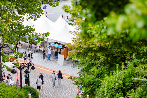 Students visiting various booths against the backdrop of the green campus. ⓒ 토토사이트 순수익 University Media Strategy Center