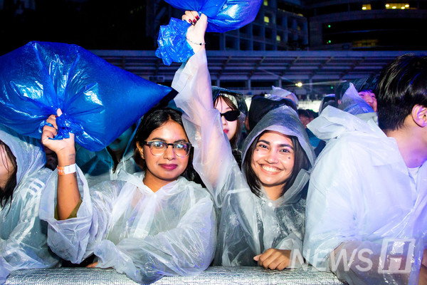 ▲ Students in raincoats wave blue cheering bags in support of the performance. 