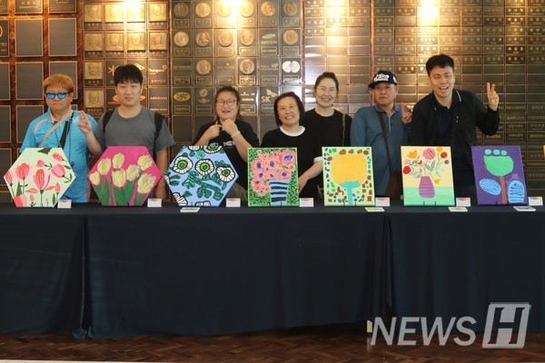 ﻿▲ 신본관 1층에 전시된 작품들과 함께 기념사진을 촬영하는 최 씨와 작가들의 모습. ⓒ 남경수 기자