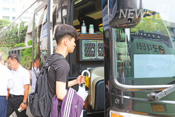 ▲ A student carrying belongings boards the homecoming bus. 