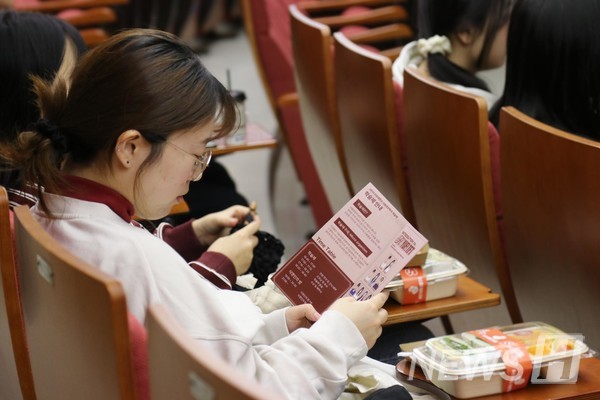 ▲ 한 학생이 소책자를 읽으며 행사 순서를 확인하고 있다.