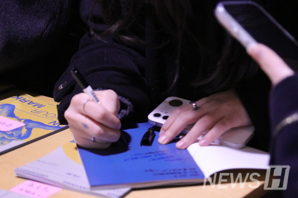 ▲ An attendee writes in the guest book, leaving messages of celebration and encouragement. 
