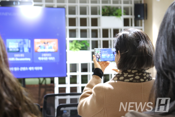 ▲ 한 선배가 후배들의 성과 발표 장면을 경청하며 스마트폰으로 촬영하고 있다.